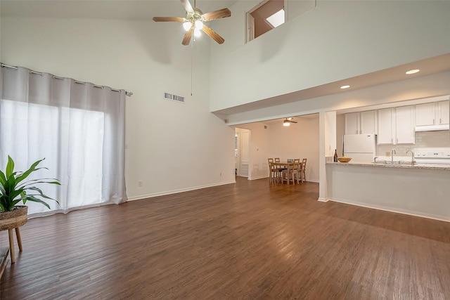 unfurnished living room with ceiling fan, dark hardwood / wood-style flooring, and high vaulted ceiling