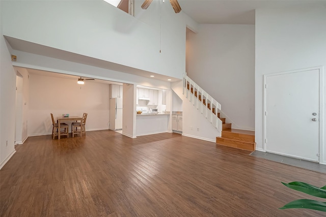 unfurnished living room with ceiling fan, high vaulted ceiling, and dark wood-type flooring