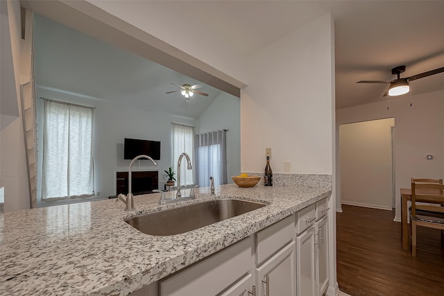 kitchen with light stone countertops, sink, dark hardwood / wood-style flooring, vaulted ceiling, and white cabinets