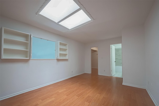 spare room with built in shelves and light hardwood / wood-style floors