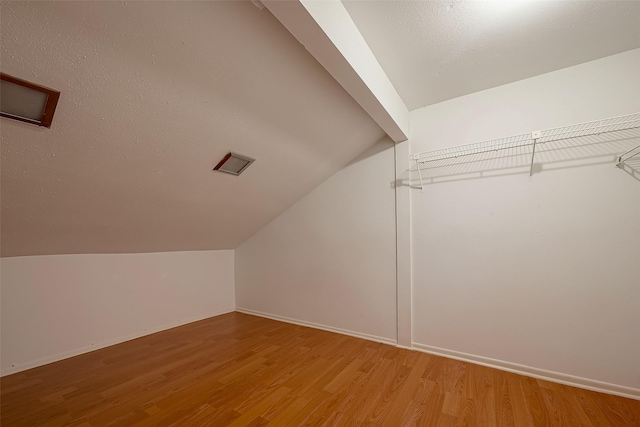 additional living space featuring hardwood / wood-style flooring and vaulted ceiling