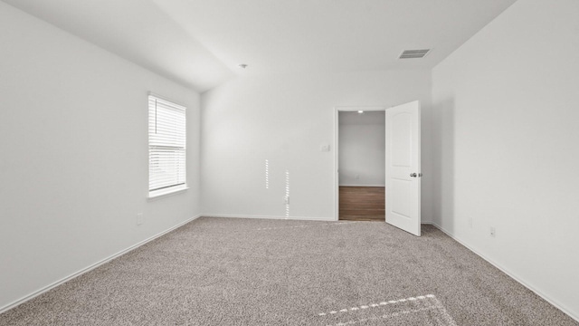 carpeted spare room featuring lofted ceiling