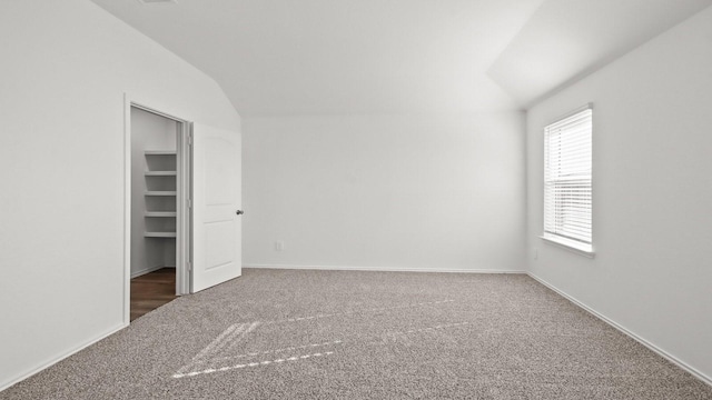 unfurnished bedroom featuring carpet flooring, a closet, and vaulted ceiling