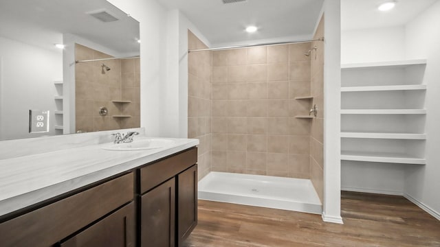 bathroom featuring a tile shower, vanity, and hardwood / wood-style floors