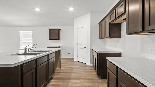 kitchen featuring hardwood / wood-style floors, dark brown cabinetry, a kitchen island with sink, and sink