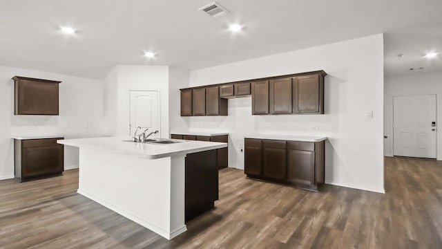 kitchen with dark brown cabinetry, sink, an island with sink, and dark hardwood / wood-style floors