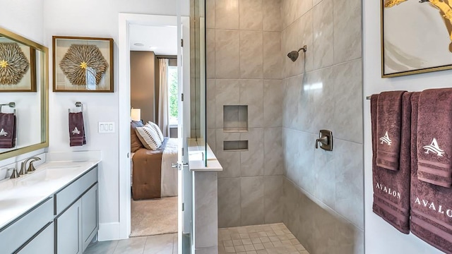 bathroom featuring tile patterned flooring, a tile shower, and vanity