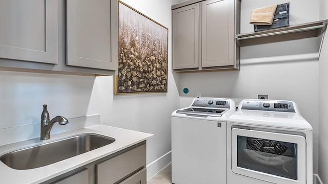 laundry room with cabinets, washer and clothes dryer, and sink