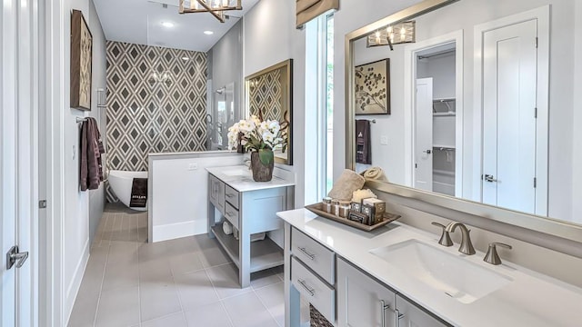 bathroom with tile patterned flooring, vanity, a tub to relax in, and a notable chandelier