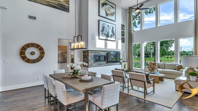 dining room featuring a towering ceiling, dark hardwood / wood-style flooring, a wealth of natural light, and ceiling fan