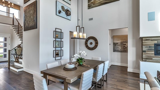 dining space featuring dark wood-type flooring, a high ceiling, and a chandelier