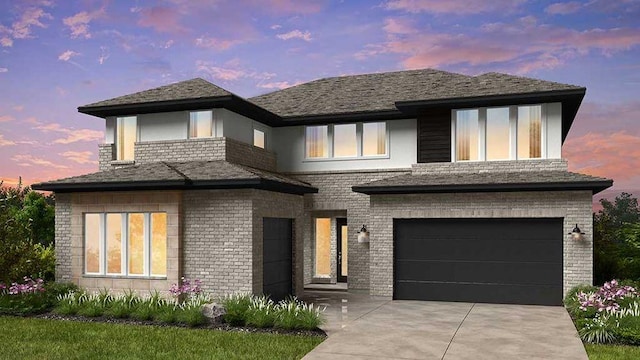 prairie-style house with a garage, brick siding, driveway, and a shingled roof