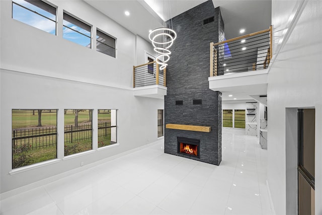 tiled living room with a stone fireplace, a chandelier, and a high ceiling