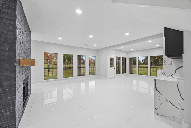 living room with a wealth of natural light, a fireplace, and light tile patterned floors