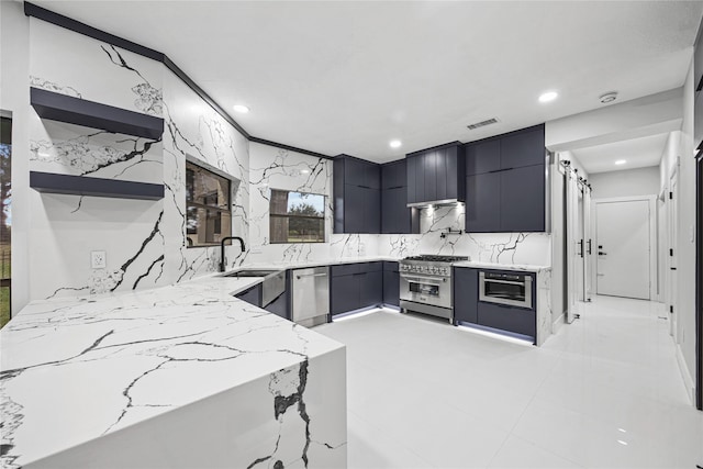 kitchen featuring backsplash, sink, appliances with stainless steel finishes, light stone counters, and kitchen peninsula