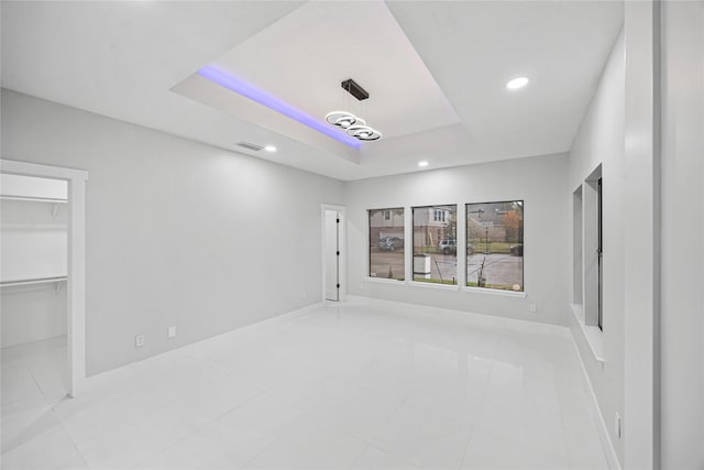 interior space featuring a raised ceiling, a spacious closet, a closet, and light tile patterned flooring