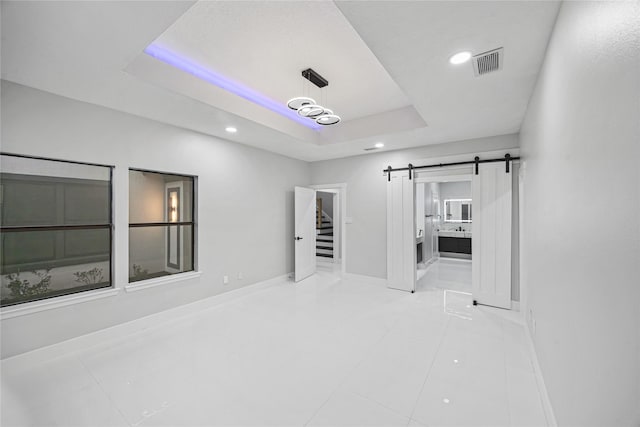 tiled spare room with a raised ceiling and a barn door