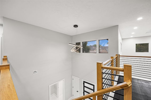 staircase featuring hardwood / wood-style floors, a chandelier, and a textured ceiling