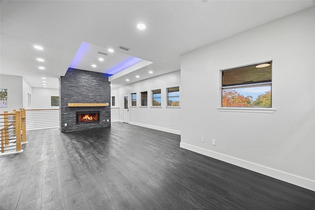 unfurnished living room with plenty of natural light, a fireplace, and dark hardwood / wood-style floors