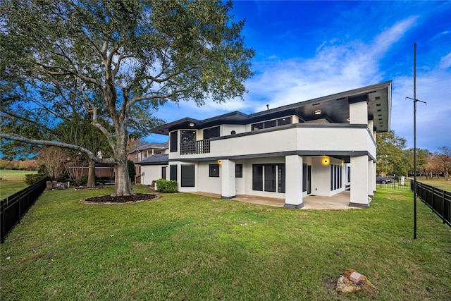 back of property with a lawn, a patio area, and a balcony