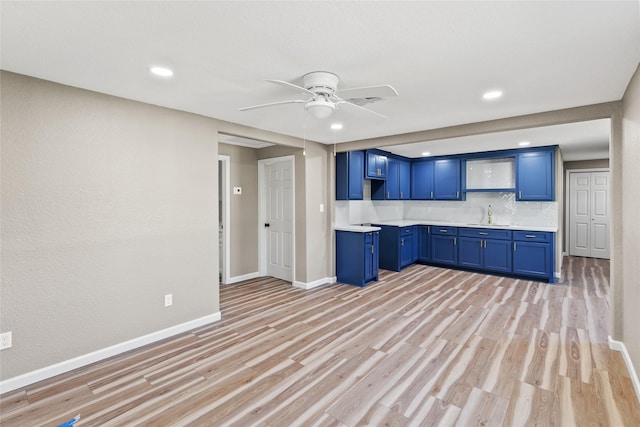 kitchen with tasteful backsplash, blue cabinets, ceiling fan, and light hardwood / wood-style floors