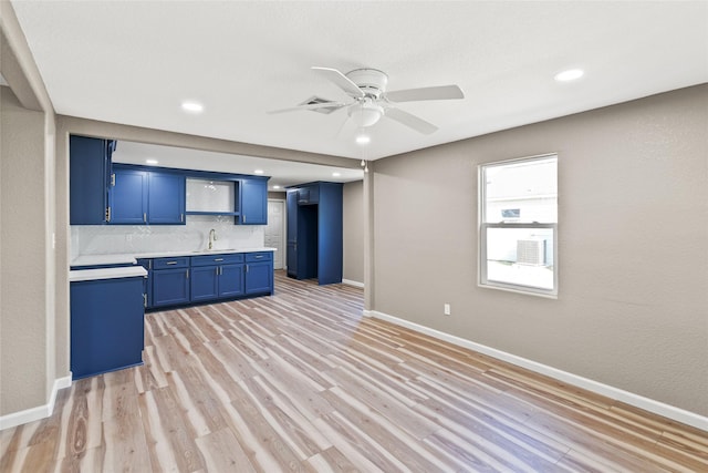 kitchen with light wood-type flooring, blue cabinets, ceiling fan, and sink