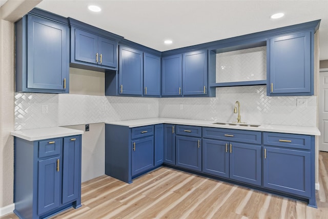 kitchen with blue cabinetry, light wood-type flooring, tasteful backsplash, and sink