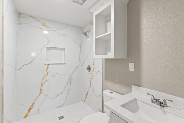 bathroom with tiled shower, vanity, and toilet