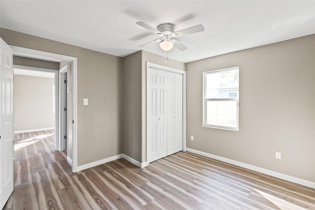 unfurnished bedroom with ceiling fan, a closet, and light hardwood / wood-style flooring