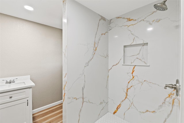 bathroom with a tile shower, vanity, and hardwood / wood-style flooring