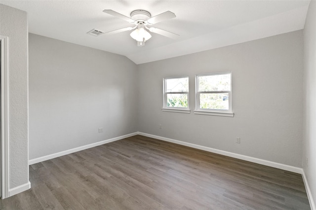 empty room featuring dark hardwood / wood-style flooring, vaulted ceiling, and ceiling fan