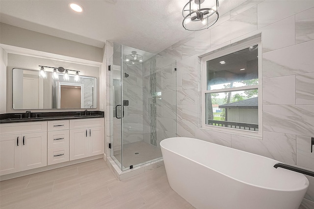 bathroom with vanity, a textured ceiling, independent shower and bath, and tile walls