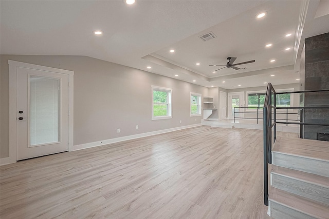 living room with a raised ceiling, ceiling fan, and light wood-type flooring