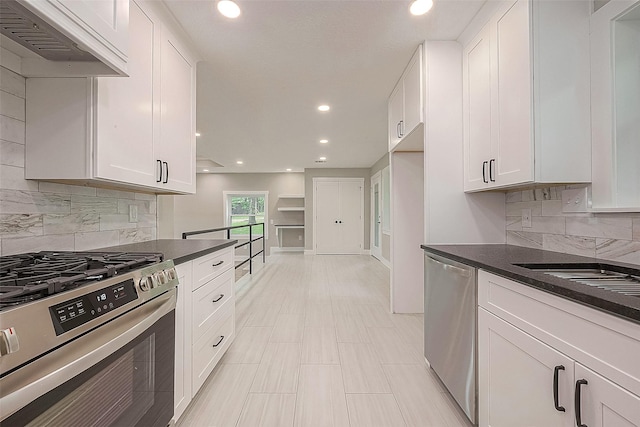 kitchen with decorative backsplash, white cabinetry, custom range hood, and appliances with stainless steel finishes