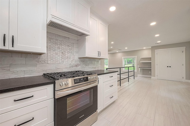 kitchen with tasteful backsplash, white cabinetry, premium range hood, and gas range