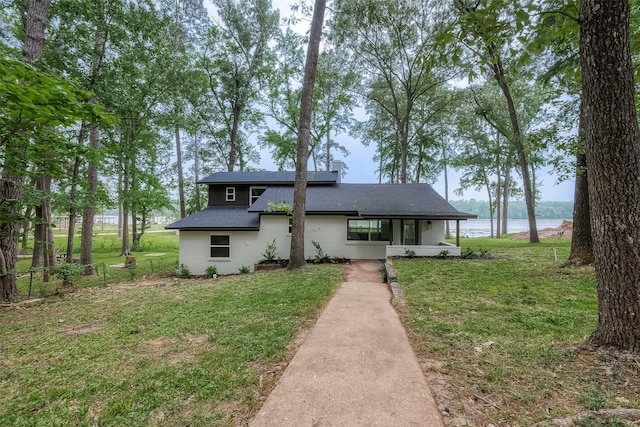 view of front of house with a front lawn and a water view