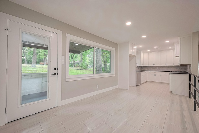 kitchen with white cabinets, decorative backsplash, stainless steel dishwasher, and sink