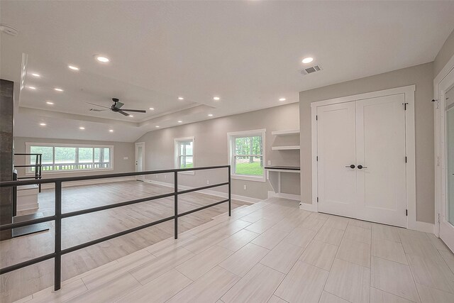 hallway with a tray ceiling and plenty of natural light