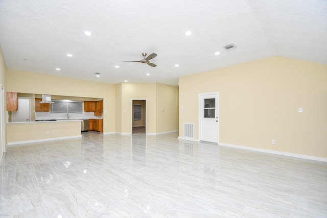 unfurnished living room with a textured ceiling, ceiling fan, sink, and vaulted ceiling