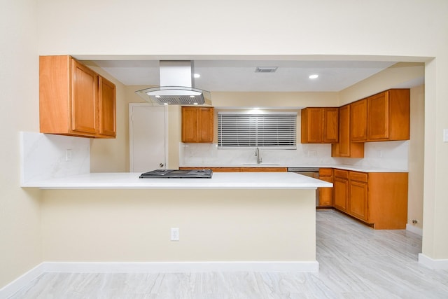 kitchen with island range hood, kitchen peninsula, sink, and stainless steel gas cooktop