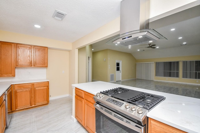 kitchen featuring ceiling fan, stainless steel appliances, vaulted ceiling, a textured ceiling, and island range hood