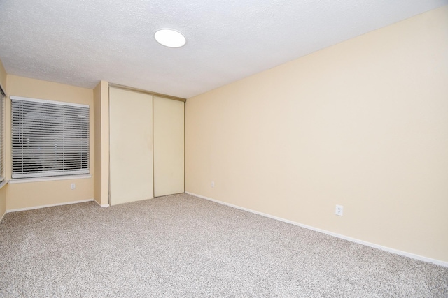 unfurnished bedroom with carpet, a textured ceiling, and a closet