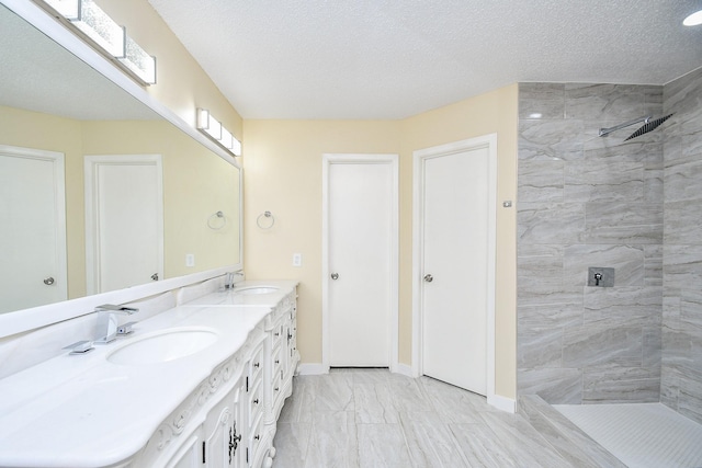 bathroom with vanity, a textured ceiling, and tiled shower