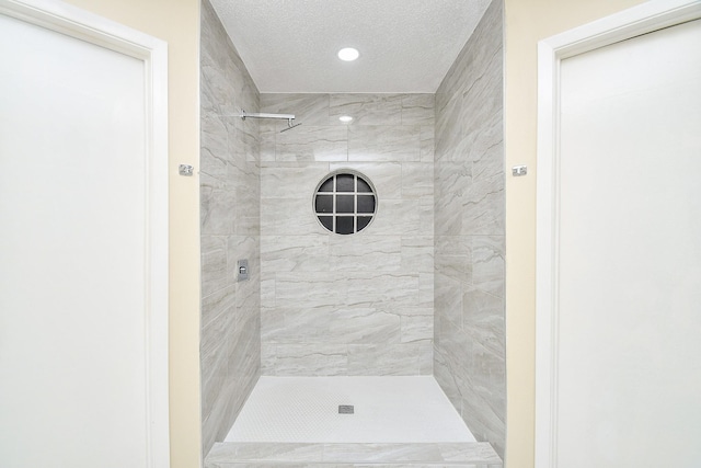 bathroom featuring tiled shower and a textured ceiling