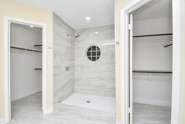 bathroom featuring a textured ceiling and tiled shower