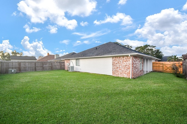 rear view of house featuring central AC unit and a lawn