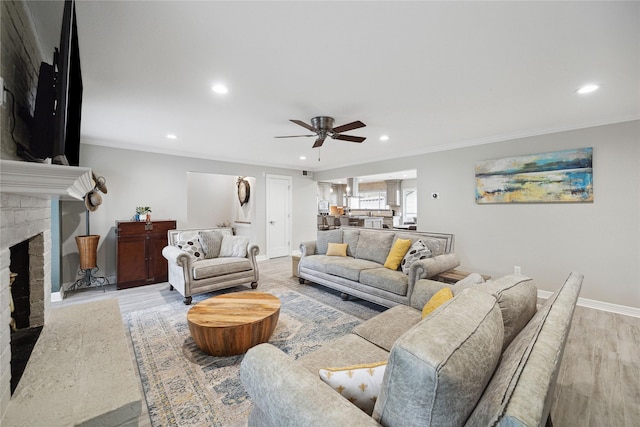 living room featuring a fireplace, light hardwood / wood-style flooring, ceiling fan, and ornamental molding