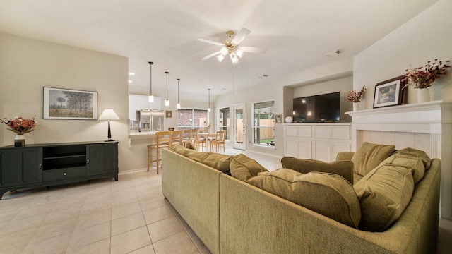 tiled living room featuring ceiling fan and a tiled fireplace