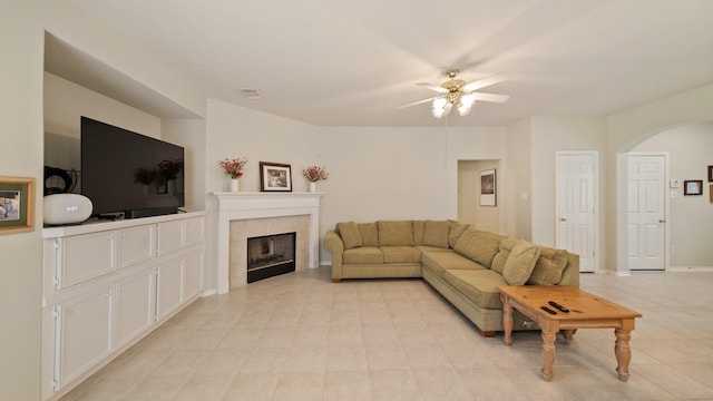 living room featuring ceiling fan, a fireplace, and light tile patterned flooring