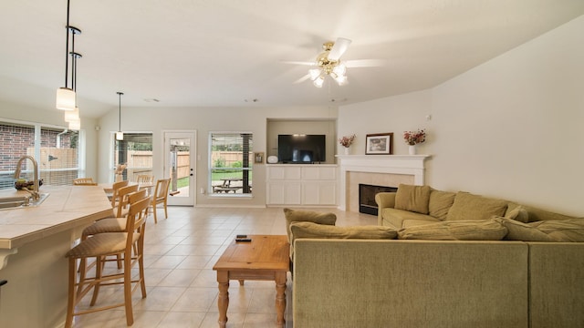 tiled living room featuring ceiling fan, lofted ceiling, and sink